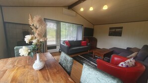 Een gezellige woonkamer met een houten eettafel, twee banken en een aan de muur bevestigde televisie.