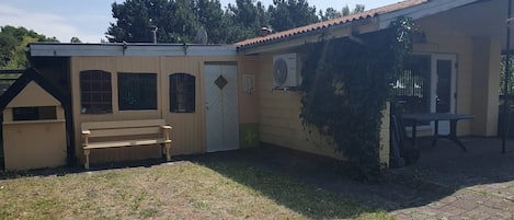 Un bâtiment doté d’un patio couvert, d’un banc et d’une petite maison de jeu.