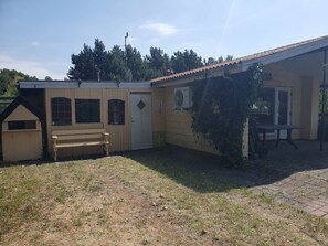 A building with a covered patio, a bench, and a small playhouse. - Lovely summer house near Rødby (Rødby)