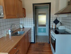 Een keuken met houten kastjes, een roestvrijstalen spoelbak, een broodrooster en een magnetron.