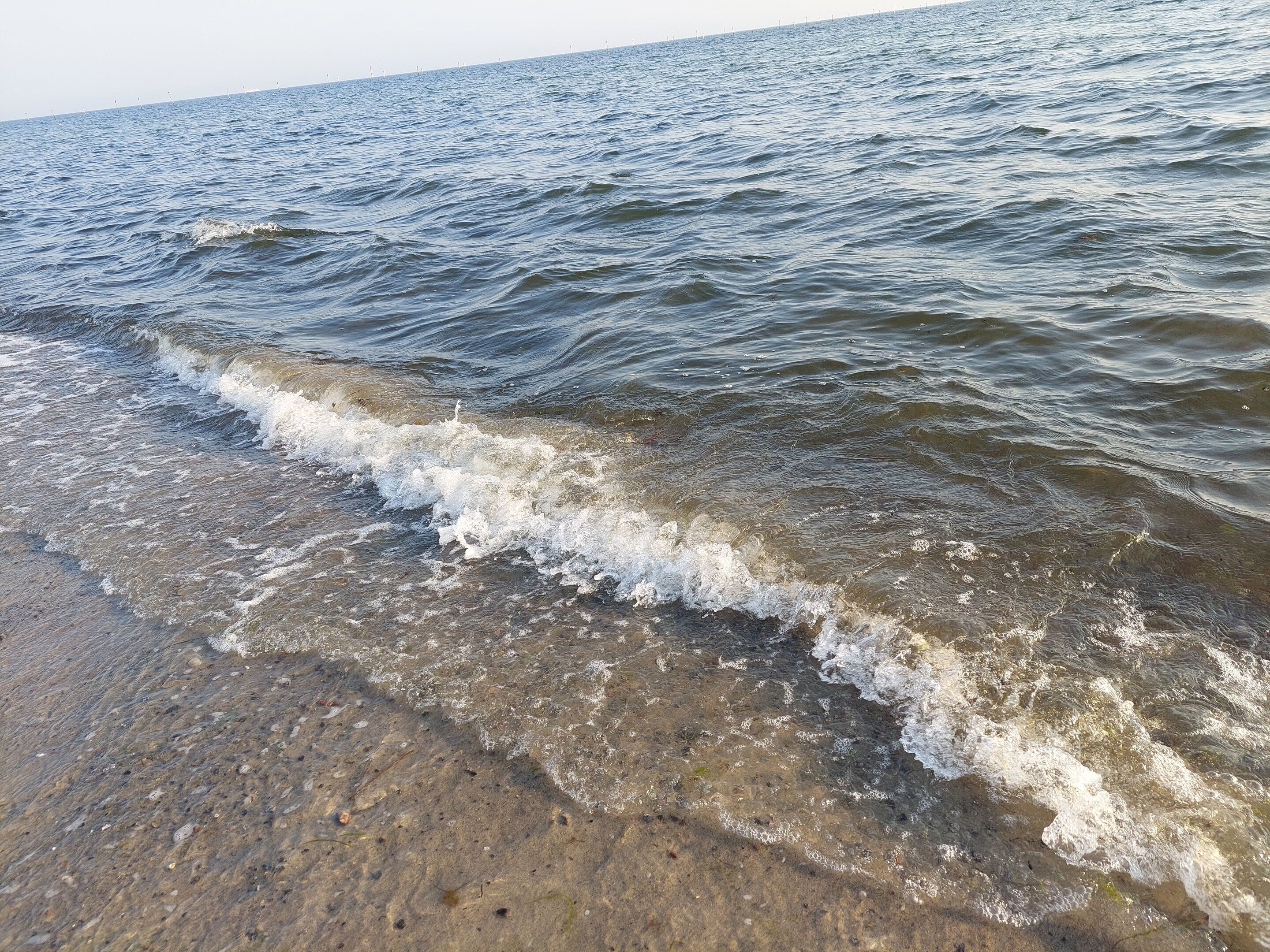 Een strand met helder water en golven.