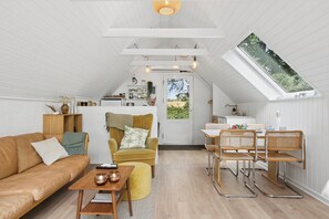 Een gezellig loft-appartement met hoge plafonds, een eethoek en een keuken die zichtbaar is door een open deur.