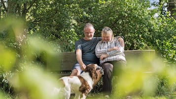 Un couple est assis sur un banc dans un parc, avec un chien.