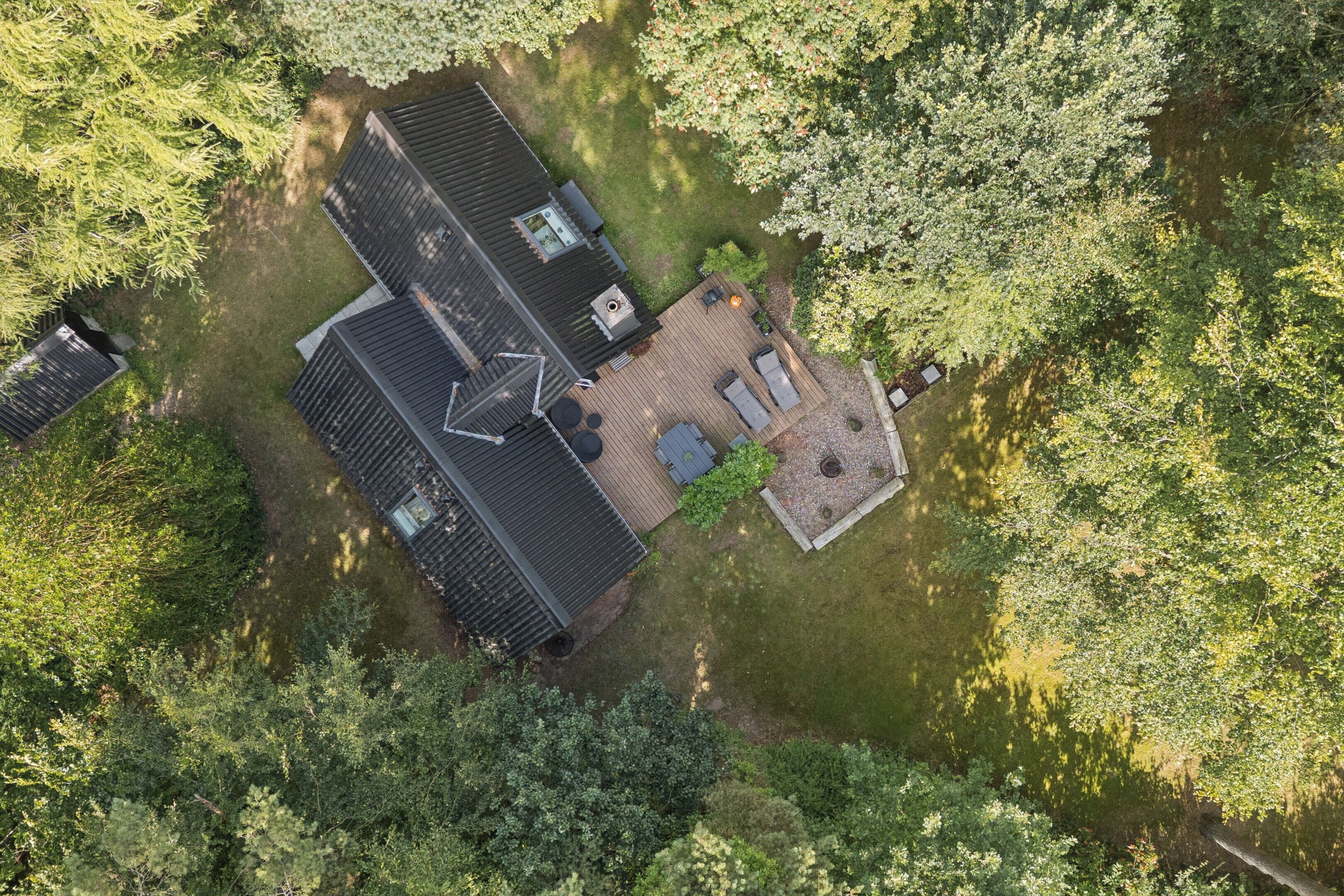 Luchtbeeld van een huis met schuin dak, terras en omheinde tuin.