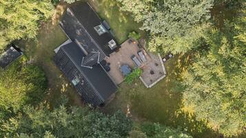 Luchtbeeld van een huis met schuin dak, terras en omheinde tuin.