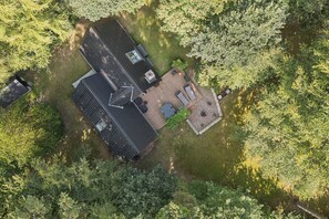 Luchtbeeld van een huis met schuin dak, terras en omheinde tuin.