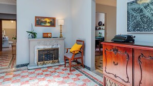 A room with a fireplace, a chair, a desk with a typewriter, and a painting on the wall. - Spacious Colonial House - 6 Bedrooms Near the Zócalo in Puebla (Heroica Puebla de Zaragoza)