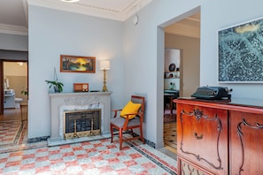 A room with a fireplace, a chair, a desk with a typewriter, and a painting on the wall. - Spacious Colonial House - 6 Bedrooms Near the Zócalo in Puebla (Heroica Puebla de Zaragoza)