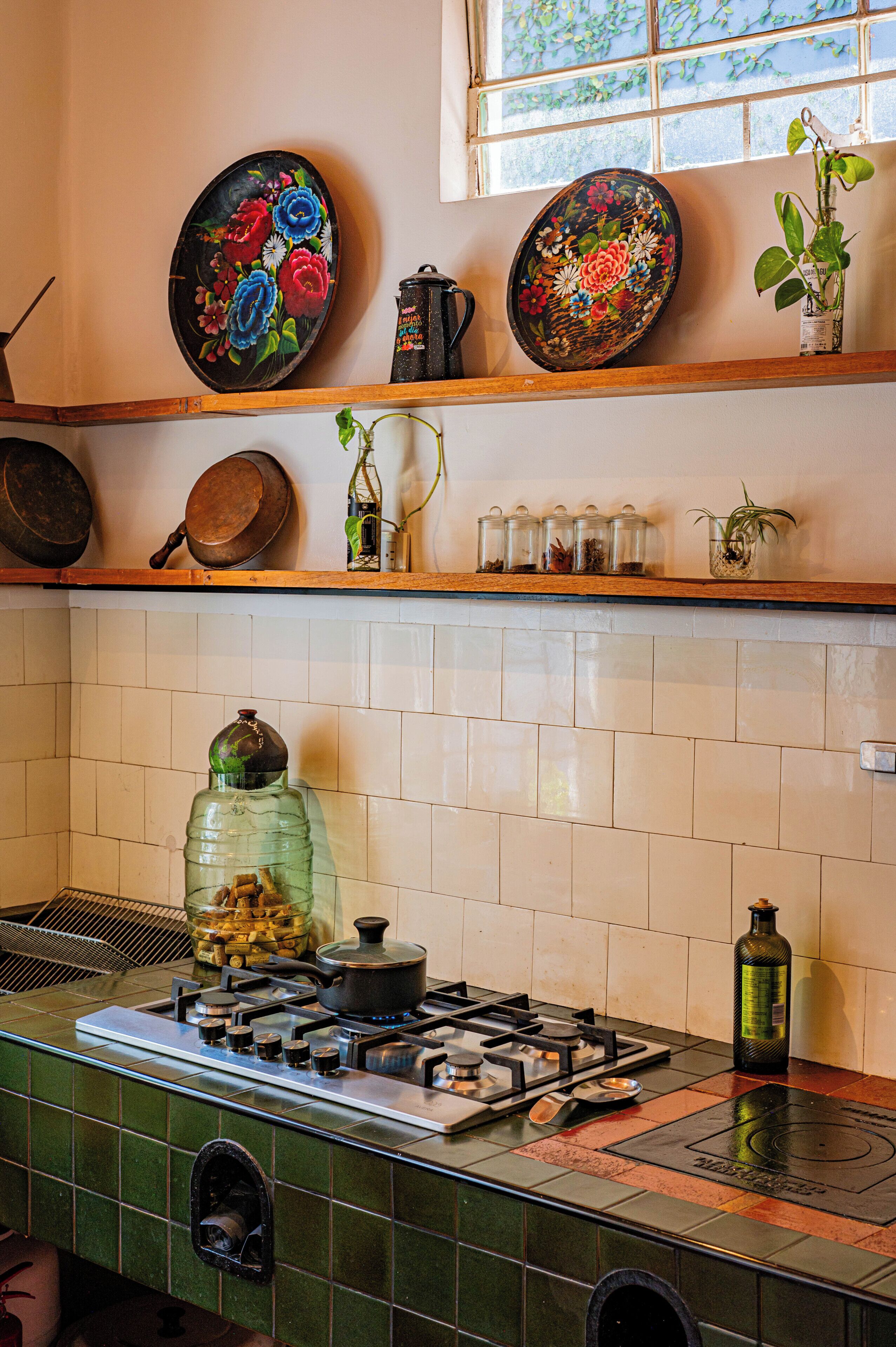 A kitchen with a gas stove, a large green water dispenser, and various kitchen utensils on the counter.
