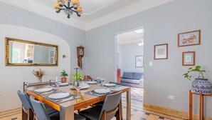 A dining area with a wooden table set for four, chairs, a mirror, a wall clock, and framed artwork. - Spacious Colonial House - 6 Bedrooms Near the Zócalo in Puebla (Heroica Puebla de Zaragoza)