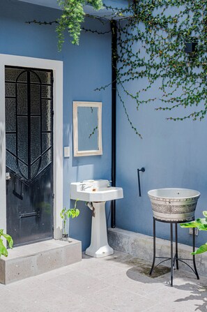 A blue exterior wall with a white door, a white pedestal sink, a round basin, and a mirror on the wall. - Spacious Colonial House - 6 Bedrooms Near the Zócalo in Puebla (Heroica Puebla de Zaragoza)