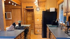 Una cocina compacta con muebles de madera, estufa empotrada y refrigerador.