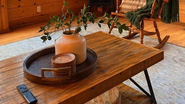 Un interior acogedor de cabaña con chimenea, muebles de madera y una vista panorámica por la ventana.