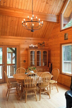 A wooden cabin interior with a dining table, chairs, a chandelier, and a cabinet with glass doors. - Charming Log Cabin Tucked Away Near Cle Elum (Cle Elum)