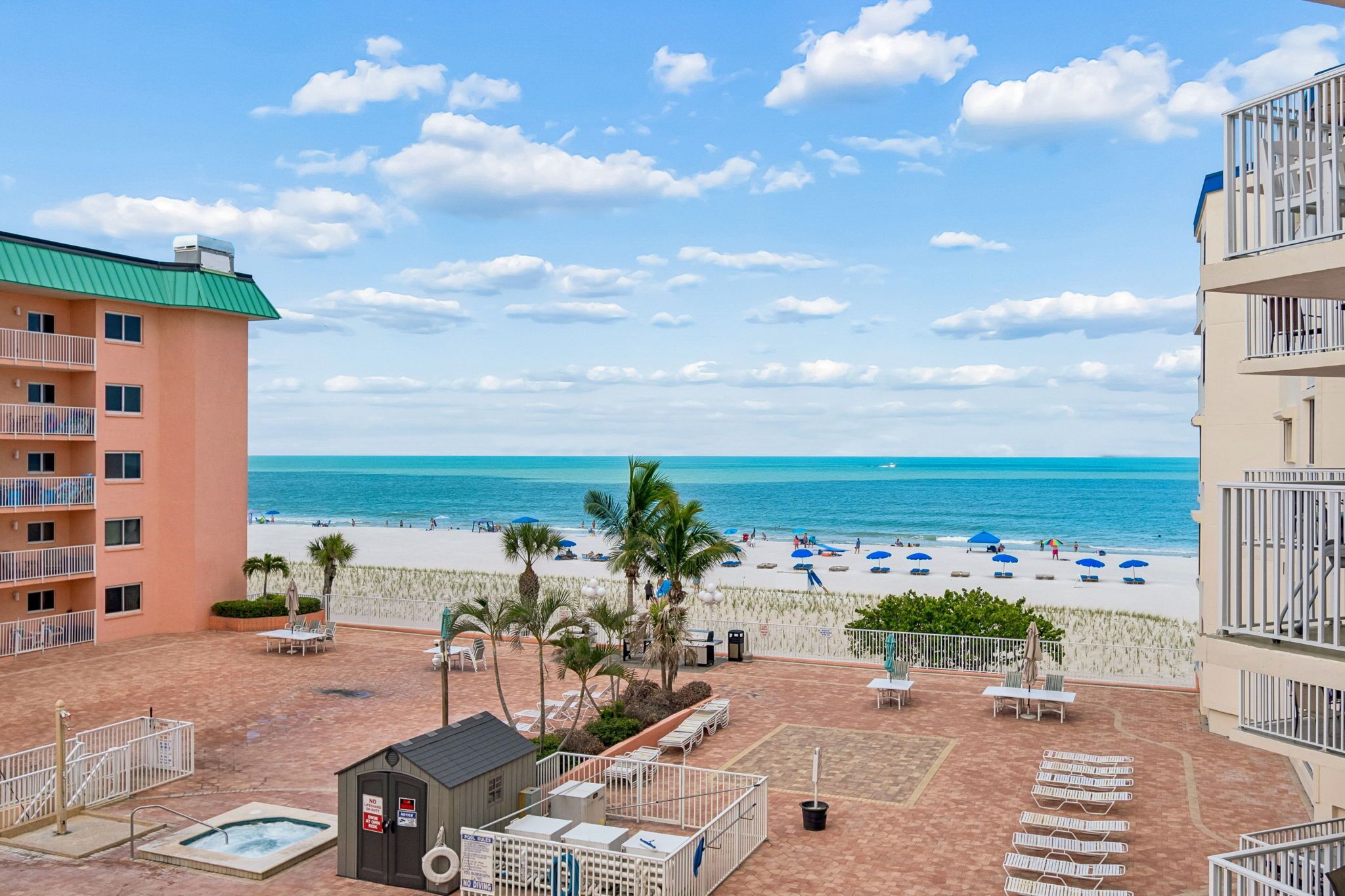 A beachfront property with a pool, outdoor seating, and a view of the ocean.