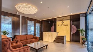 Um lobby moderno com balcão de recepção, área de estar e amplas janelas.