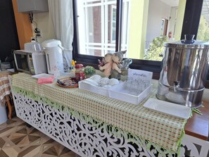 A breakfast buffet setup with a variety of food items, a coffee machine, and a decorative elephant figurine. - Sai Pan House Phrae (Sung Men)