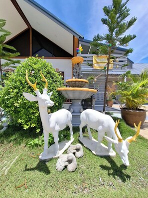 A garden with a fountain, two deer statues, and a potted plant. - Sai Pan House Phrae (Sung Men)