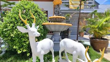 A garden with a fountain, two deer statues, and a potted plant.