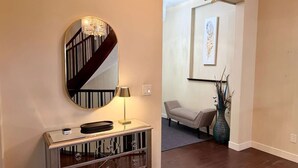 A hallway with a mirror, a lamp, a sofa, and a vase.
