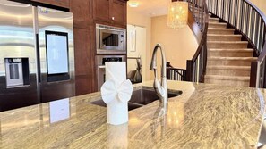 A modern kitchen with stainless steel appliances, a marble countertop, and a built-in sink. - Mountain View Retreat w/ Fireplace in Aspen Hills (Calgary)