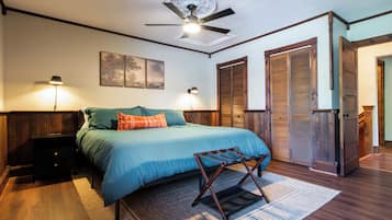 A bedroom with a bed, two wall-mounted lamps, a ceiling fan, and a large window.