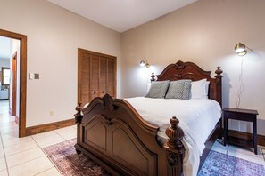 Ein Schlafzimmer mit einem hölzernen Bett, zwei Nachttischlampen, einem Nachttisch und einem gemusterten Teppich.