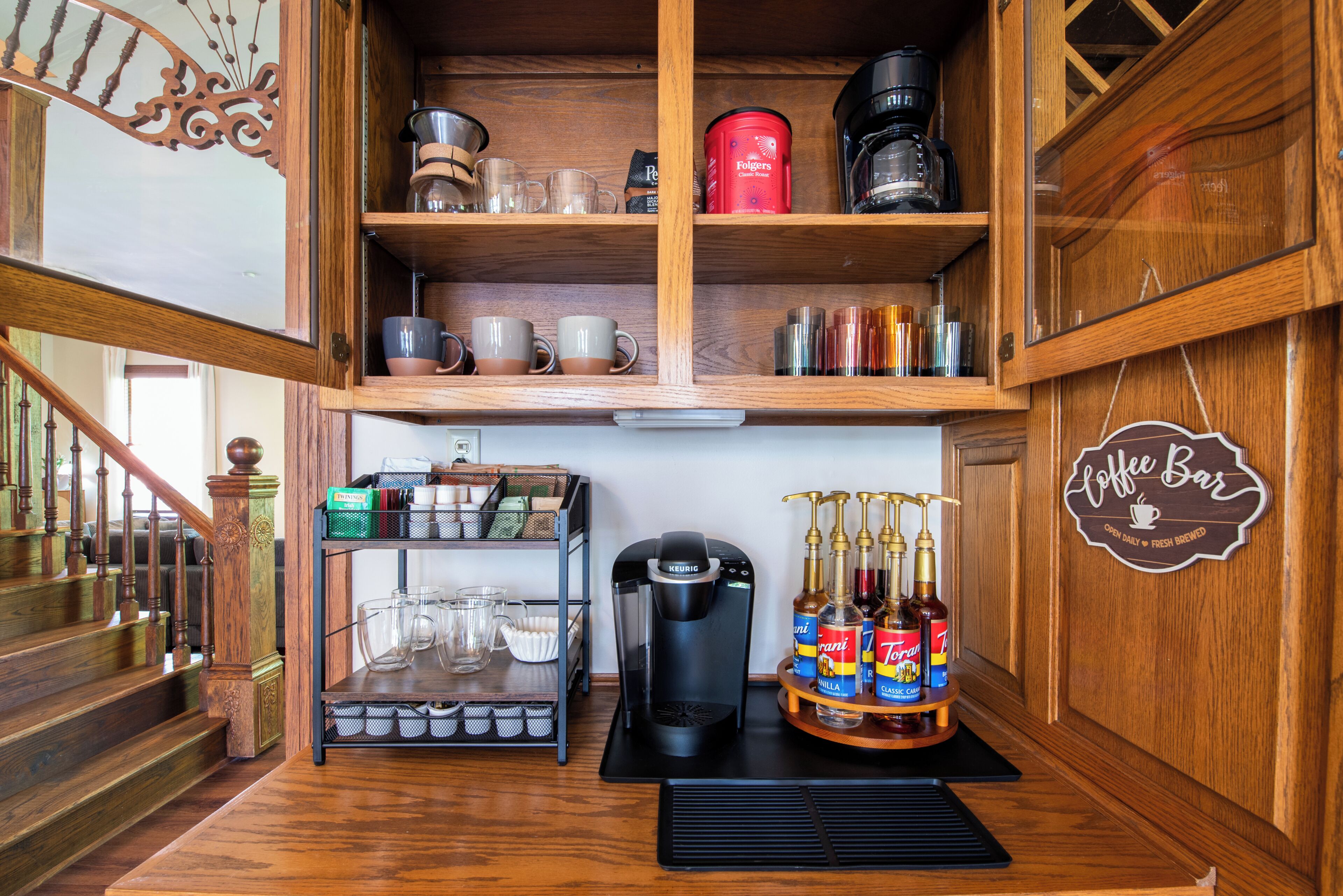 Ein Bereich mit einer Kaffeebar, einer Keurig-Kaffeemaschine, Folgers-Kaffee und verschiedenen Kaffeetassen.
