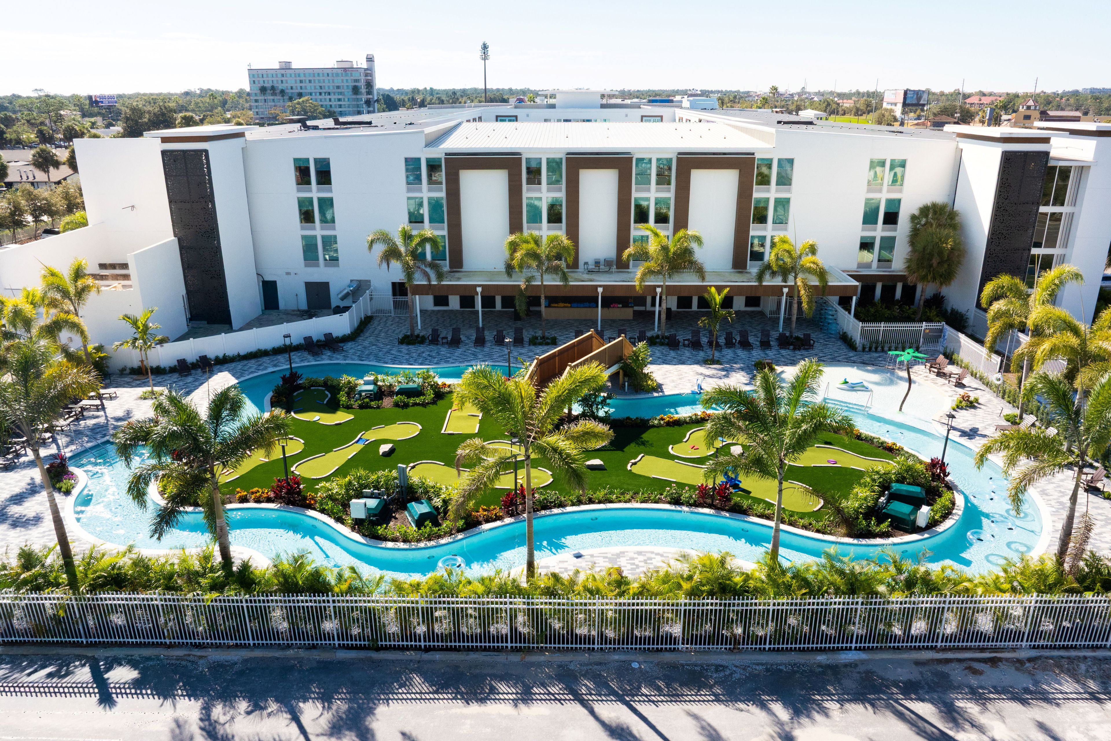 A hotel with a swimming pool, palm trees, and a view of the city.