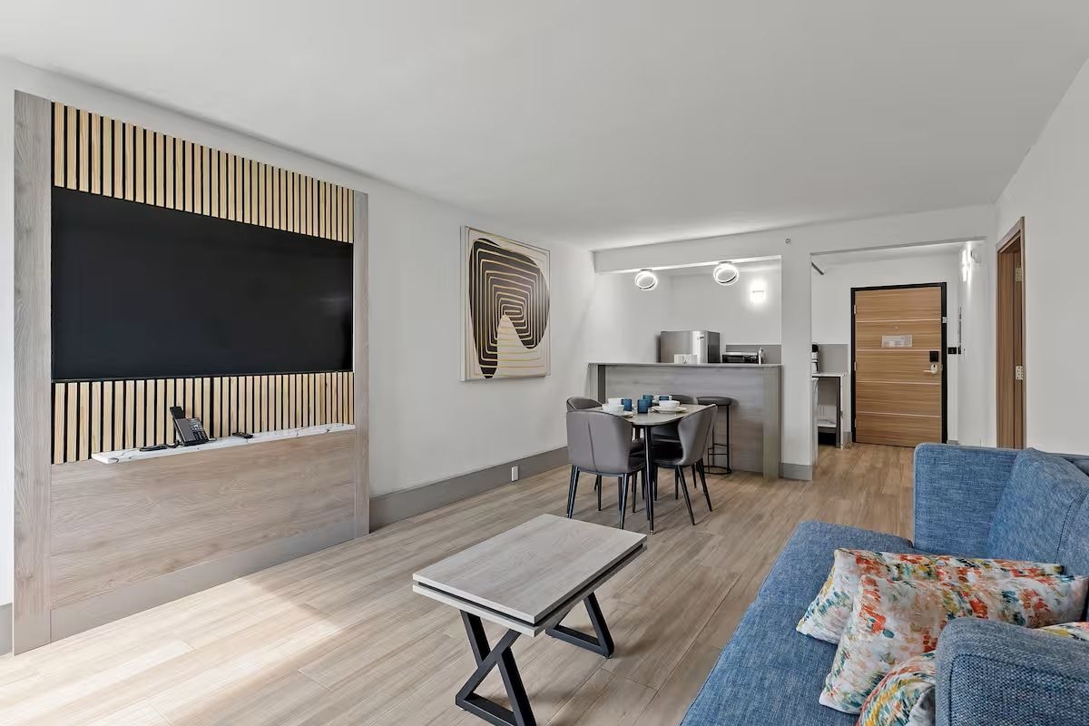 Een moderne woonkamer met een bank, een salontafel, en een eethoek met stoelen en een tafel.