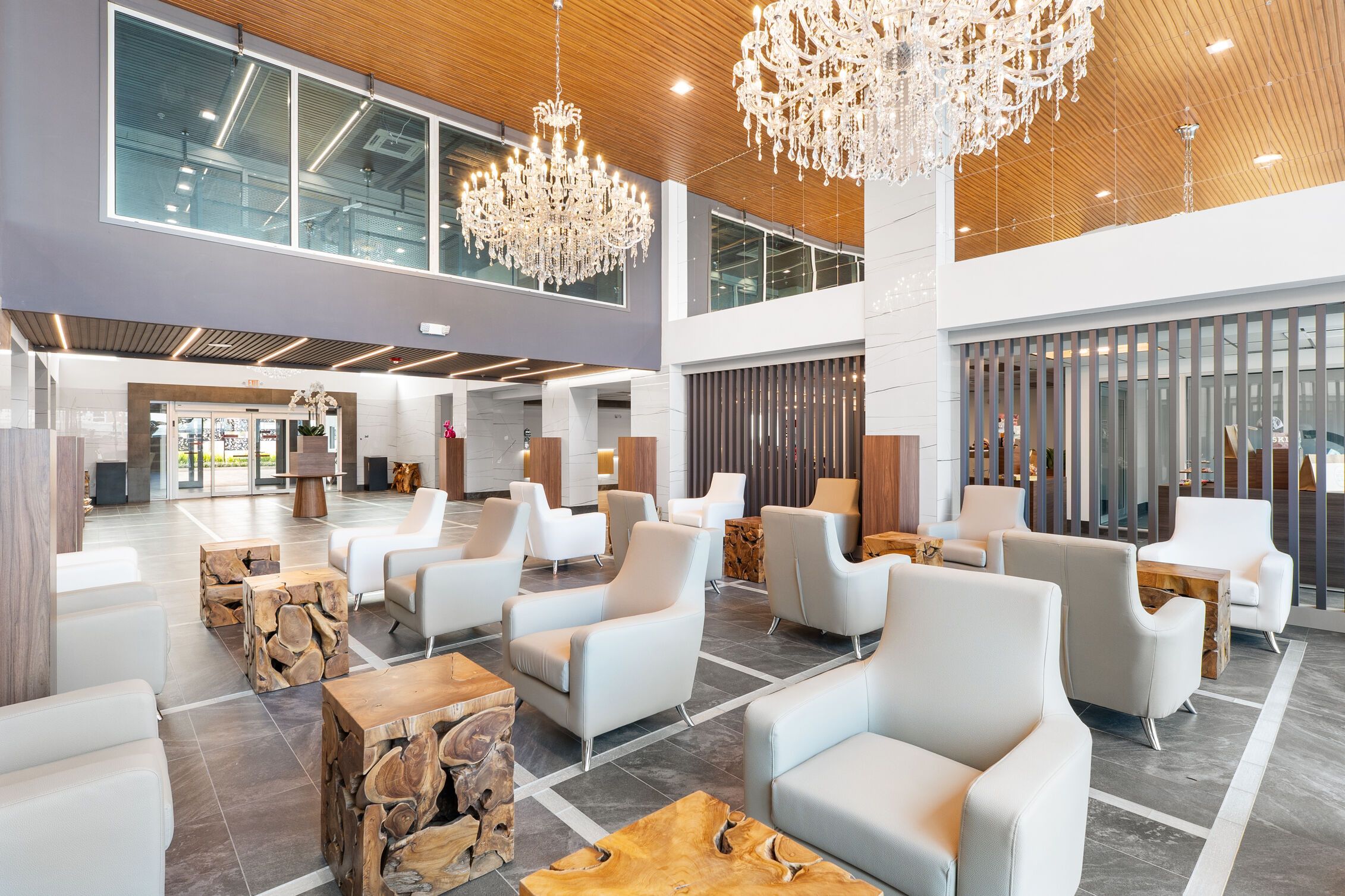 A spacious lobby with modern seating, a grand chandelier, and a high ceiling.