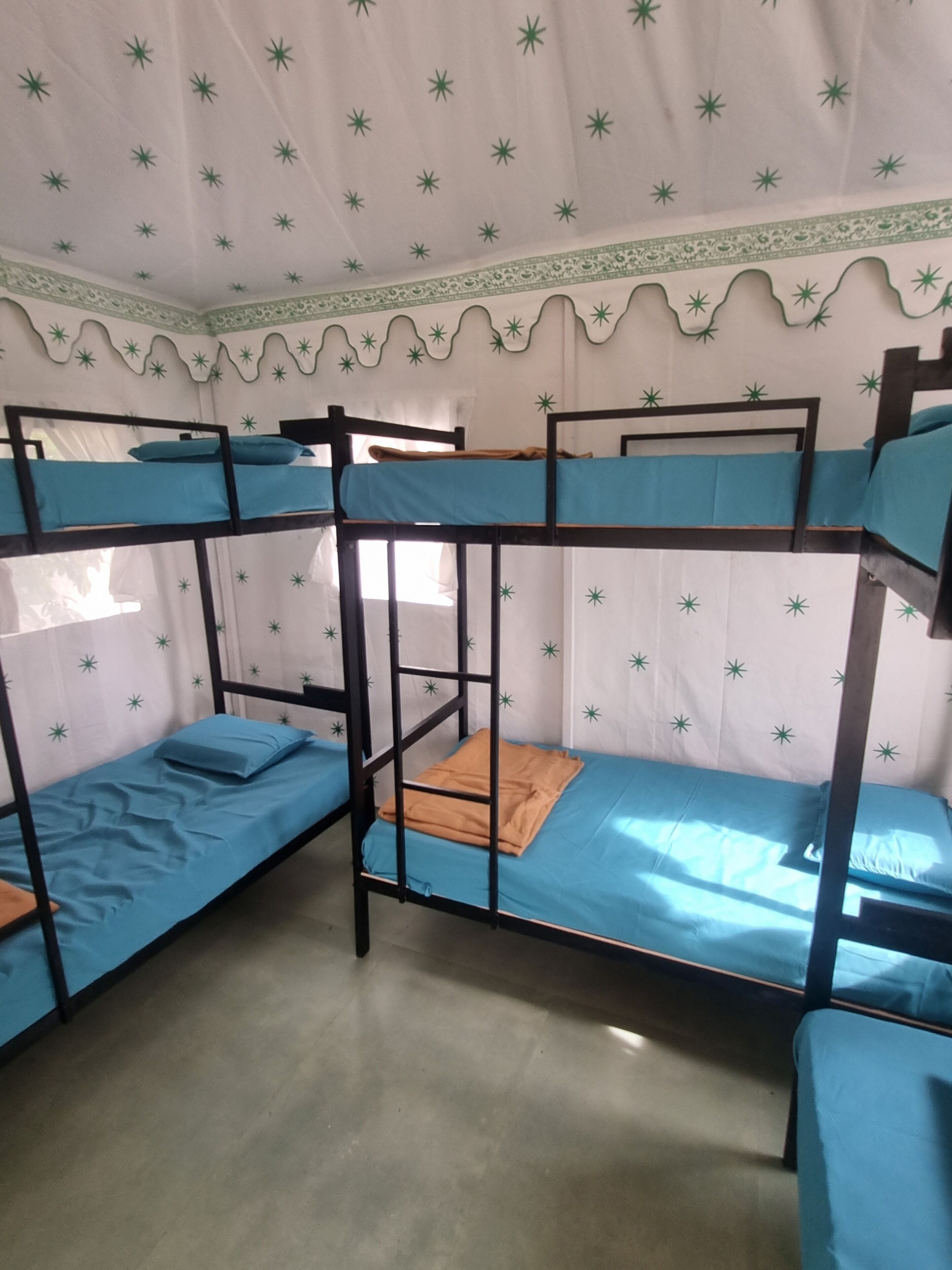 A bunk bed room with a patterned ceiling and a window.
