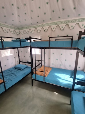 A bunk bed room with a patterned ceiling and a window.