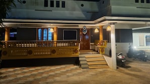A building with a staircase leading to a door, a balcony with railings, and a parked scooter.