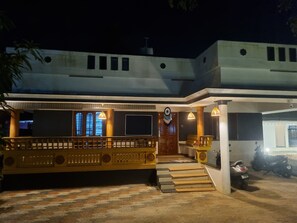 A building with a staircase leading to a door, a balcony with railings, and a parked scooter.