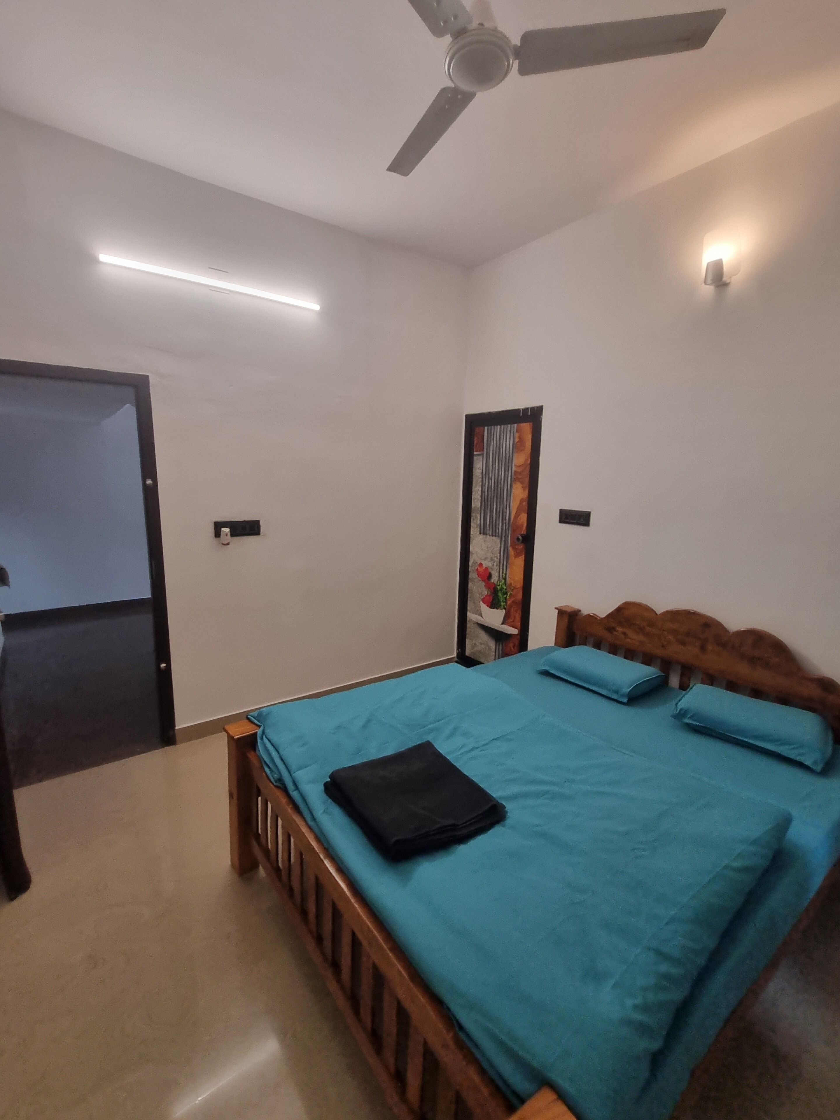 Un dormitorio con una cama, ventilador de techo y una puerta.