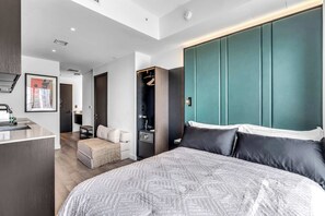 Ein modernes Hotelzimmer mit einem großen Bett, einem Schrank, einem Schreibtisch und einer Sitzecke.