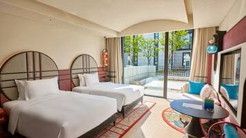 A hotel room with two beds, a small round table, and a view of the outside.