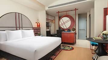 A modern hotel room with a large bed, a desk, and a round mirror.