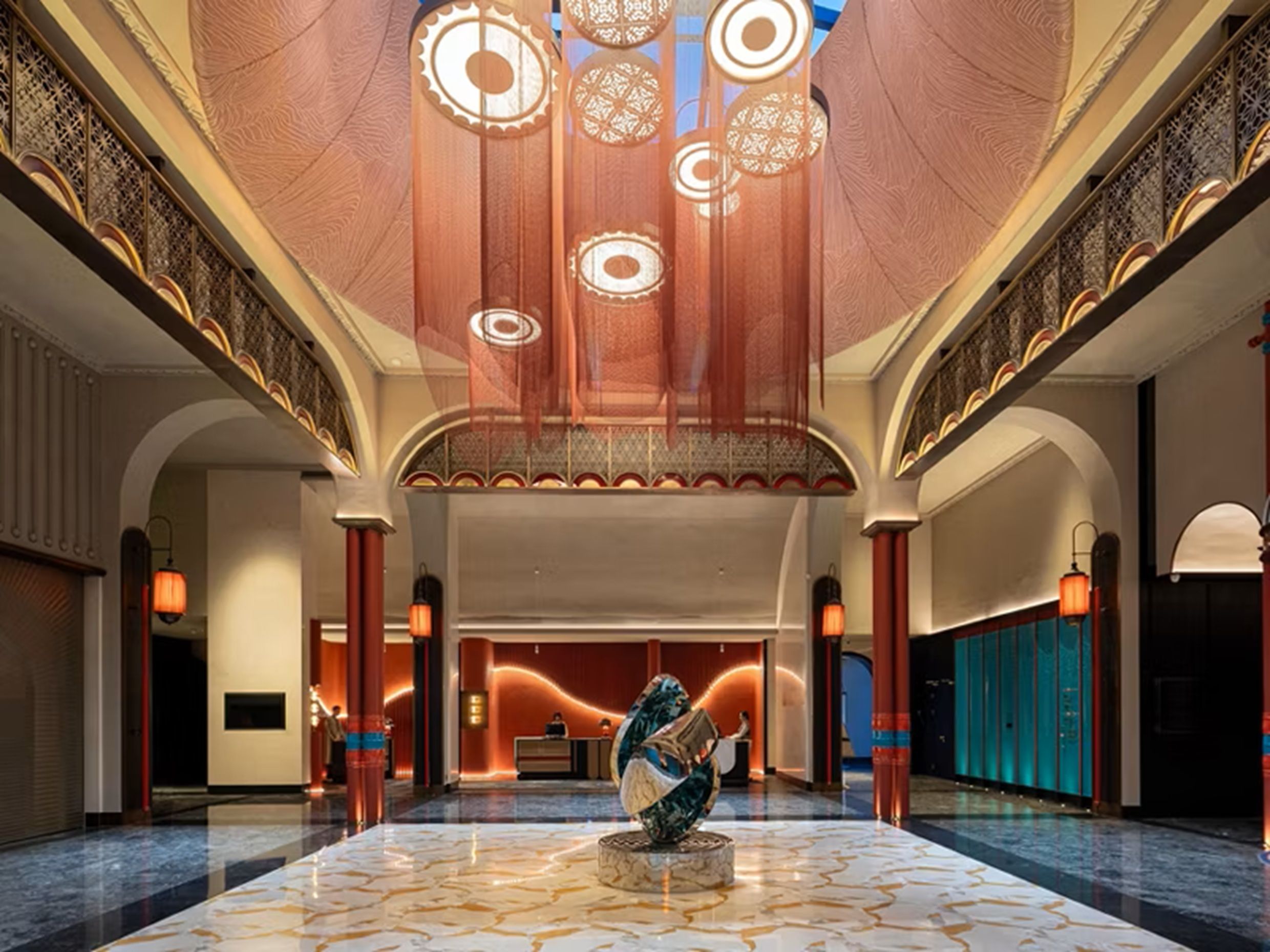 A spacious lobby with a marble floor, a reception desk, and a large decorative sculpture.