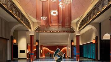 A spacious lobby with a marble floor, a reception desk, and a large decorative sculpture.