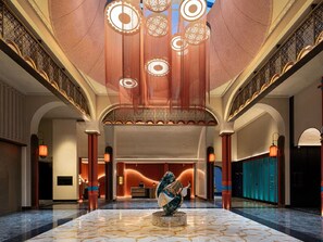 A spacious lobby with a marble floor, a reception desk, and a large decorative sculpture.