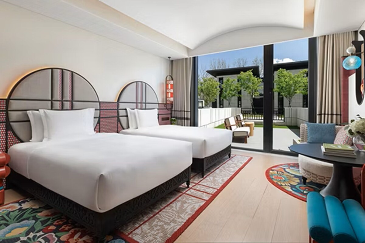 Une chambre d’hôtel moderne, dotée d’un grand lit, d’un bureau et offrant une vue sur l’extérieur.