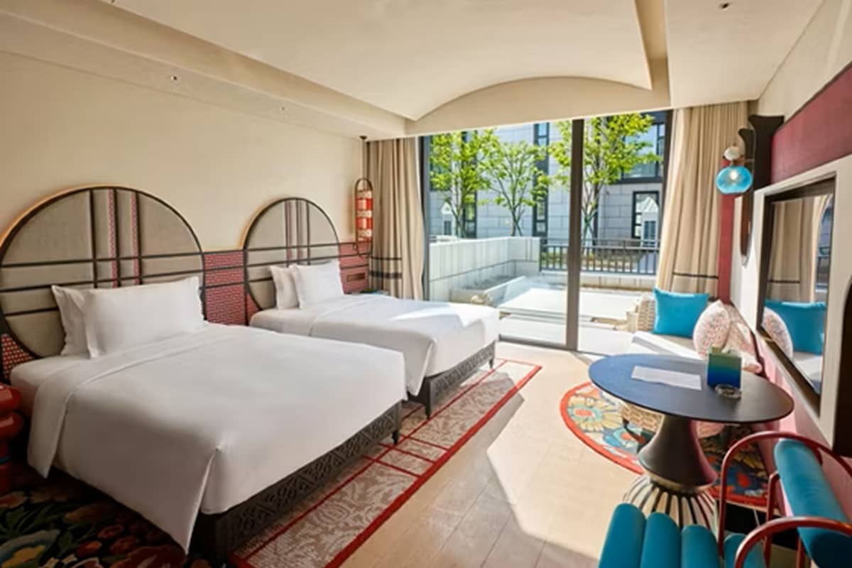 Et hotelværelse med to senge, et rundt bord og udsigt ud.