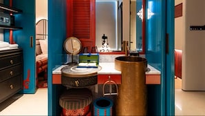 Une salle de bain avec un grand miroir, un lavabo rond et un porte-serviettes rouge.