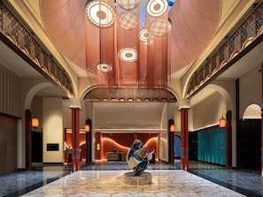 En rummelig lobby med marmorgulv, en receptionsdisk og en stor dekorativ skulptur.