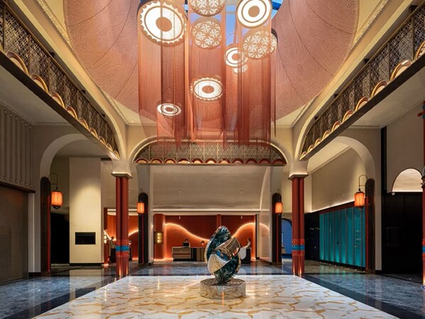 A spacious lobby with a marble floor, a reception desk, and a large decorative sculpture. - Hotel Indigo Sayram Lake by IHG (Bole)