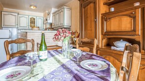 A dining table set with plates, a bottle, and a vase of flowers. - Lovely apartment in binic-étables-sur-mer (Binic-Étables-Sur-Mer)