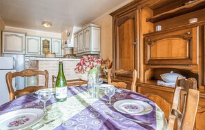 A dining table set with plates, a bottle, and a vase of flowers. - Lovely apartment in binic-étables-sur-mer (Binic-Étables-Sur-Mer)