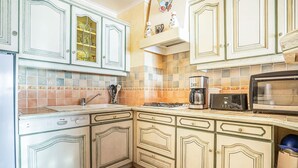 A kitchen with white cabinetry, a gas stove, a coffee maker, a toaster, and a microwave. - Lovely apartment in binic-étables-sur-mer (Binic-Étables-Sur-Mer)